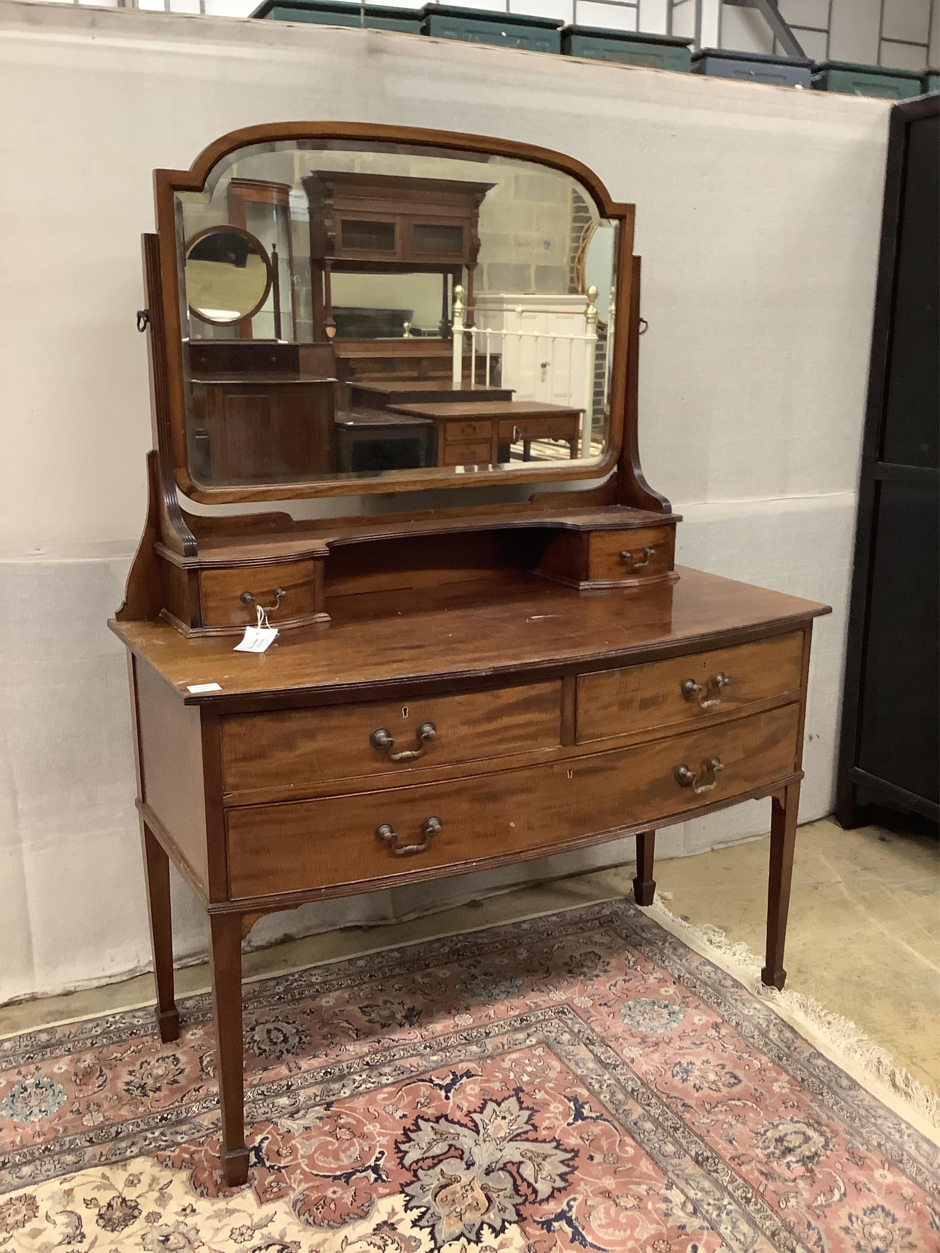 An early 20th century mahogany bowfront dressing table, fitted two short and one long drawer with brass loop handles and square tapered legs with spade feet, width 116cm, depth 57cm, height 156cm. Condition - fair